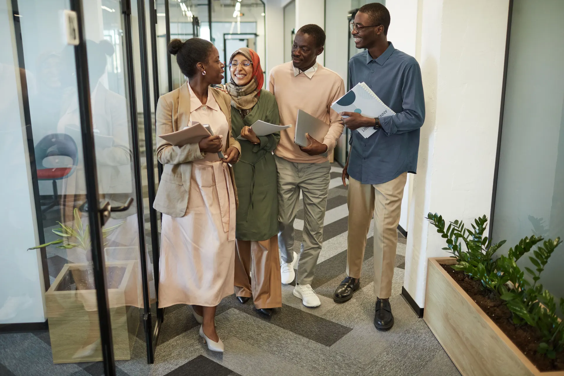 Four colleagues walking and talking through a glass office doorway